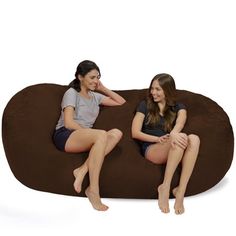 two young women sitting on a bean bag chair with their feet propped up against each other