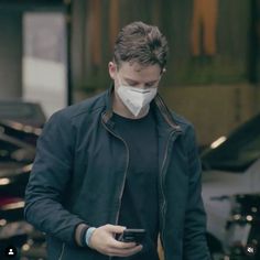 a man wearing a face mask while looking at his cell phone