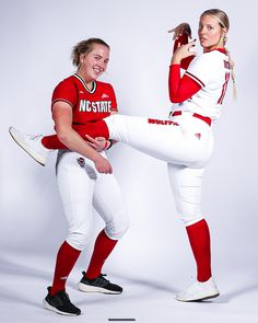 two women in baseball uniforms posing for a photo with one leg up and the other leg down