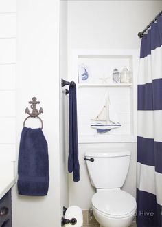 a white toilet sitting in a bathroom next to a blue and white shower curtain with an anchor on it