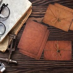 three brown envelopes tied with twine and eyeglasses on top of a wooden table