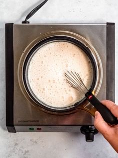 a person is using a whisk to stir something in a saucepan on the stove