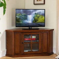 a flat screen tv sitting on top of a wooden entertainment center next to a window