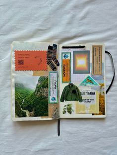 an open notebook with stamps and other items on it, including a green jacket in the middle