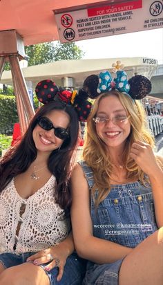 two women sitting next to each other wearing minnie mouse ears