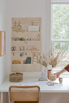 a woman sitting at a white desk in front of a window with lots of items on it