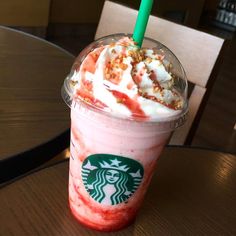 a starbucks drink with strawberries and whipped cream on top is sitting on a table