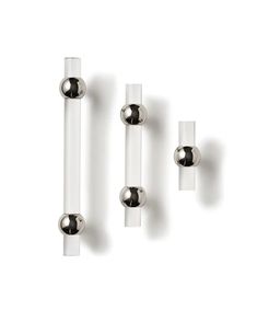 three glass and chrome door handles on a white wall with two balls in the middle