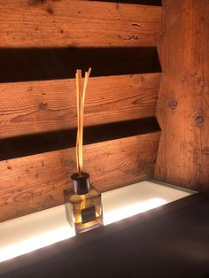 a small glass vase sitting on top of a table next to a wooden wall and floor