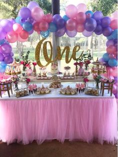 a table topped with lots of balloons next to a sign that says'one '