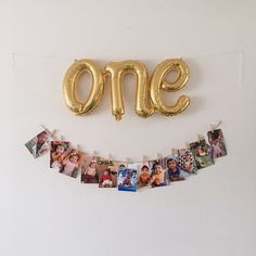 a gold balloon shaped like the number one with photos hanging from it's side