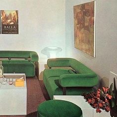 a living room filled with green couches and white tables in front of pictures on the wall