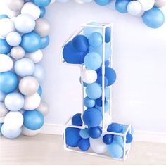 blue and white balloons are arranged around the number one balloon arch