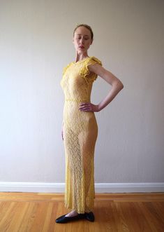 A vintage 1930s yellow lace gown with a small collar, ruffled flutter sleeves, and a low back. The lace fabric feels like cotton. There are no fasteners, but the fabric has give to fit over bust/shoulders. Size: xxs to small Bust: 28-34" Waist: 26-32" (will drape fine on slightly smaller, and 32" waist will need to fit over bust/shoulders because there are no fasteners at waist) Hip: 30-38" Length: 59-60" (will drape slightly shorter when dress is worn) Condition: Very good. Darkening in underarms and slight darkening at hem, but because of location, these flaws wouldn't be noticeable when dress is worn. A few tiny breaks in lace that look like part of pattern. Dress has been hand washed and presents as excellent. Fitted Lace Maxi Dress With Scalloped Details, Fitted Lace Maxi Dress With Scalloped Lace, Fitted Maxi Length Lace Dress With Scalloped Lace, Yellow Lace Dress For Evening, Yellow Lace Evening Dress, Fitted Floor-length Maxi Dress With Delicate Lace, Fitted Delicate Lace Floor-length Maxi Dress, Fitted Maxi Lace Dress With Ruffles, Fitted Maxi Length Lace Dress With Ruffles