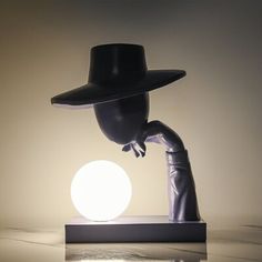 a black hat is on top of a white ball in the shape of a hand