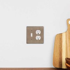 a wooden cutting board sitting next to a light switch