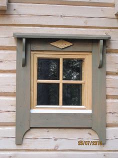 a window with wooden trim on the side of a cabin building that is made out of wood