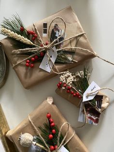 three wrapped presents tied with twine and decorated with red berries, pine cones and greenery