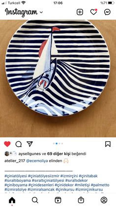 a blue and white plate with a sailboat on the front, sitting on top of a wooden table