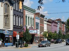 a row of buildings on the side of a street with cars parked in front of them