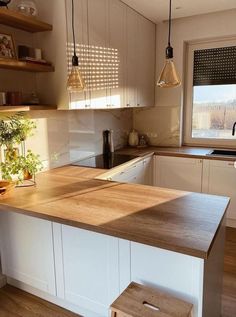 a kitchen with white cabinets and wooden counter tops, along with a small stool in front of the island