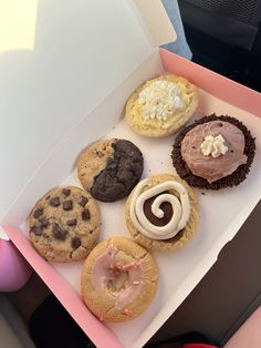 a box filled with assorted cookies and pastries on top of a pink table