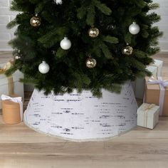 a small christmas tree in a white pot with gold and silver ornaments on it's top