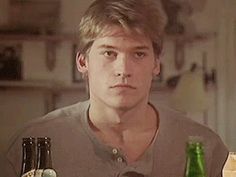 a man sitting at a table with two bottles of beer in front of his face