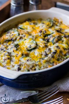 a casserole dish with meat and cheese in it on a table next to silverware