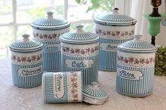 blue and white kitchen canisters sitting on top of a table next to a window