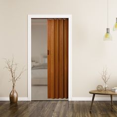 an open door in a white room with wood flooring and vases on the side table