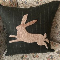 a decorative pillow with an embroidered rabbit on it