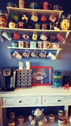 there are many cups and mugs on the shelves above the desk in this room