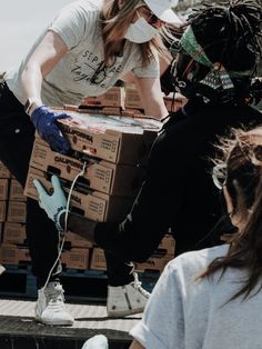 two people sitting on the back of a truck with boxes and wires in their hands