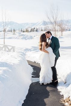 a bride and groom kissing in the snow