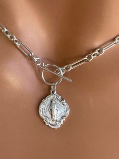 "This is a stunning thick, solid 925 sterling silver choker necklace with a unique Virgin Mary medallion that hangs from toggle clasp in front. This gorgeous Mother Mary charm measures 19x15mm and has the Miraculous Mary stamp with cross heart and stars on backside.. Made here is the USA by skilled silversmiths this pendant is absolutely incredible. This lovey sterling silver chunky chain links measure 8x4mm and 4mm, 3-1 pattern. Model is wearing a 15\" choker length. Comes in a gift box, ready Etsy Necklaces Unique, Silver Toggle Choker Necklace With Lobster Clasp, Silver Choker Chain Necklace With Toggle Clasp, Silver Toggle Clasp Chain Choker, Sterling Silver Choker With Lobster Clasp, Silver Toggle Clasp Choker Necklace, Silver Engraved Lariat Jewelry, Silver Pendant Toggle Necklace With Lobster Clasp, Elegant Silver Toggle Choker Necklace