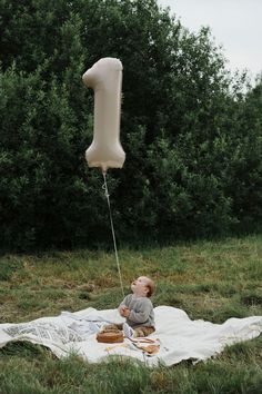 a baby sitting on a blanket with a balloon attached to it