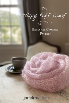 a pink scarf sitting on top of a table next to a cup and saucer