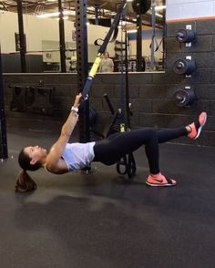 a woman is doing an exercise in the gym with a barbell on her back