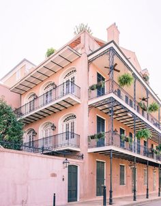 an apartment building with balconies and plants on the second story balconys is painted pink