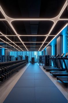 an empty gym with rows of treadmills and blue lights on the ceiling above