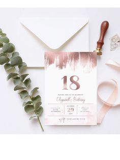 the wedding stationery is laid out next to some greenery and a rubber stamp