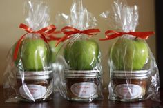 three jars filled with green apples sitting on top of a table