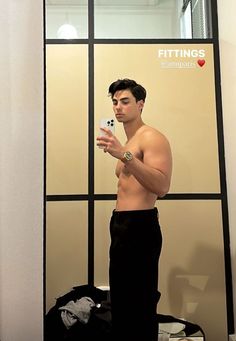 a shirtless man taking a selfie in front of a mirror