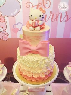 a hello kitty themed birthday cake with pink and white frosting, bows, and fondant decorations