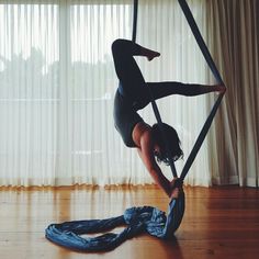 a woman doing aerial acrobatics on a pole in front of a window