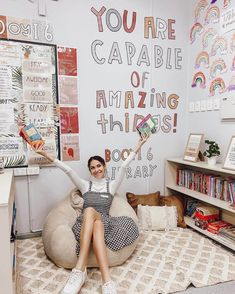 a woman sitting on top of a bean bag chair in front of a wall with writing