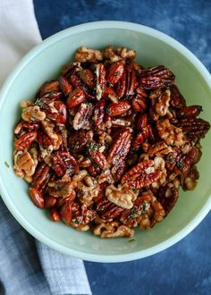 a white bowl filled with nuts on top of a blue table cloth next to a napkin