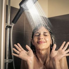 a woman is washing her face in the shower and she's holding her hands up