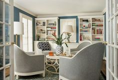 a living room filled with furniture and bookshelves next to a window covered in blinds